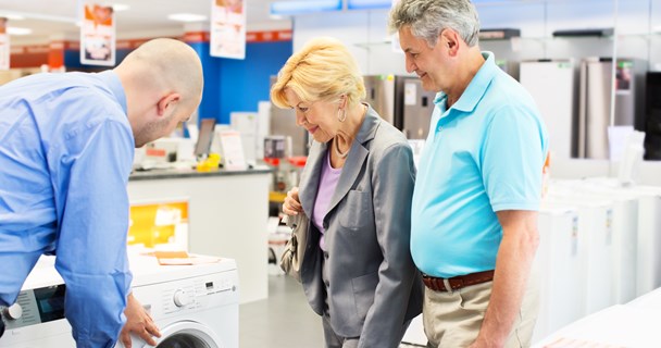 Bilde av forhandler som viser to kunder en vaskemaskin med energietikett